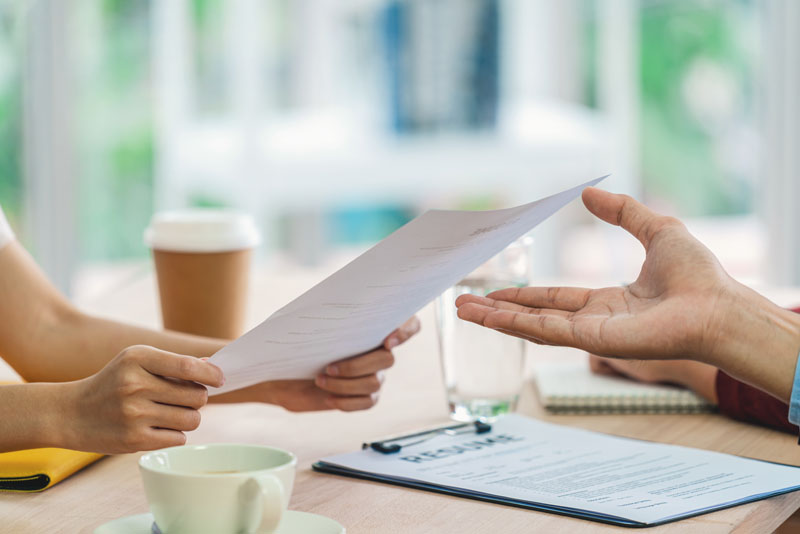Closeup Young Asian woman graduate hand holding and Submitting the resume document to two manager before start to job interview with positive motion in meeting room,Business Hiring new member concept